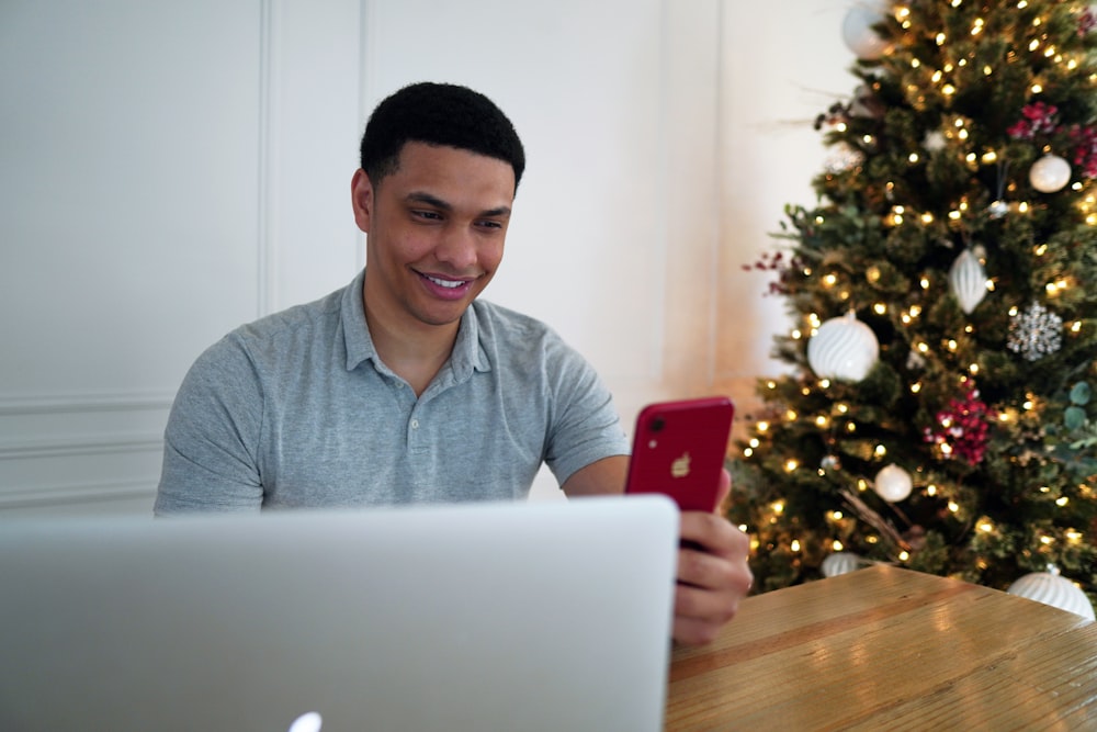 man in blue polo shirt holding red iphone 7 plus