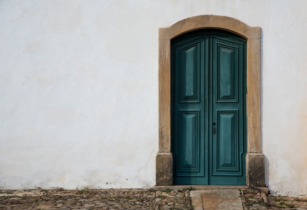 porta di legno blu su parete di cemento bianco