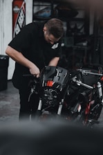 man in black crew neck t-shirt holding black and red motorcycle