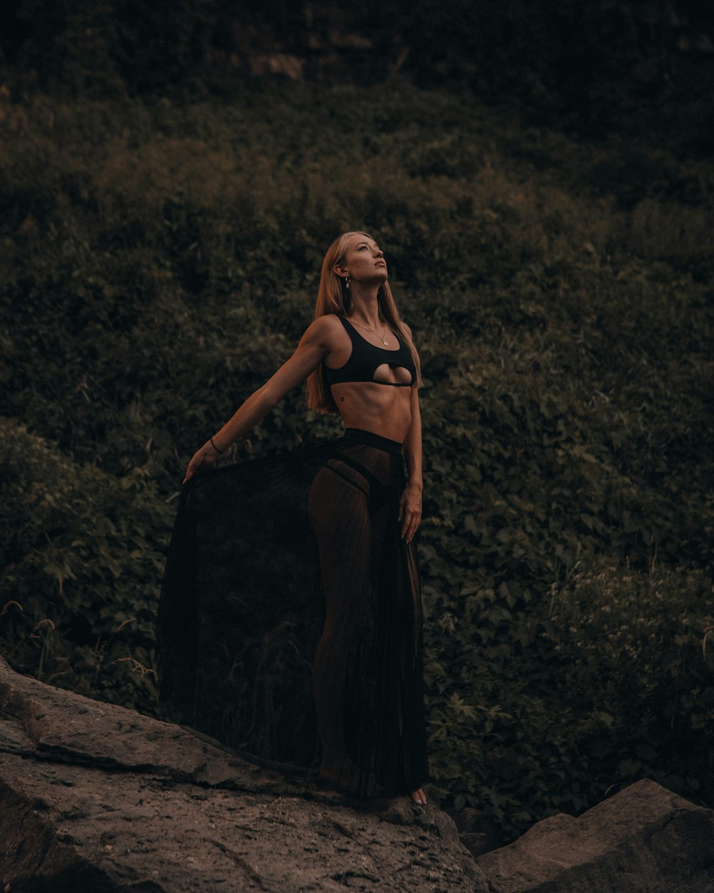 woman in black spaghetti strap dress sitting on brown rock