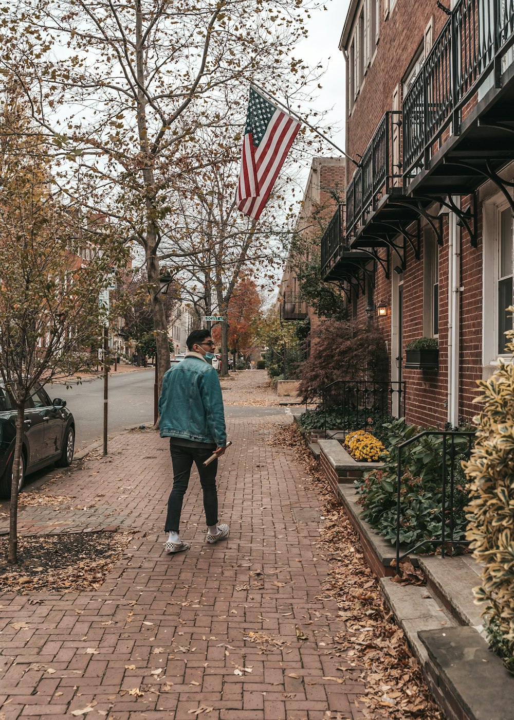 woman in blue denim jacket walking on sidewalk during daytime