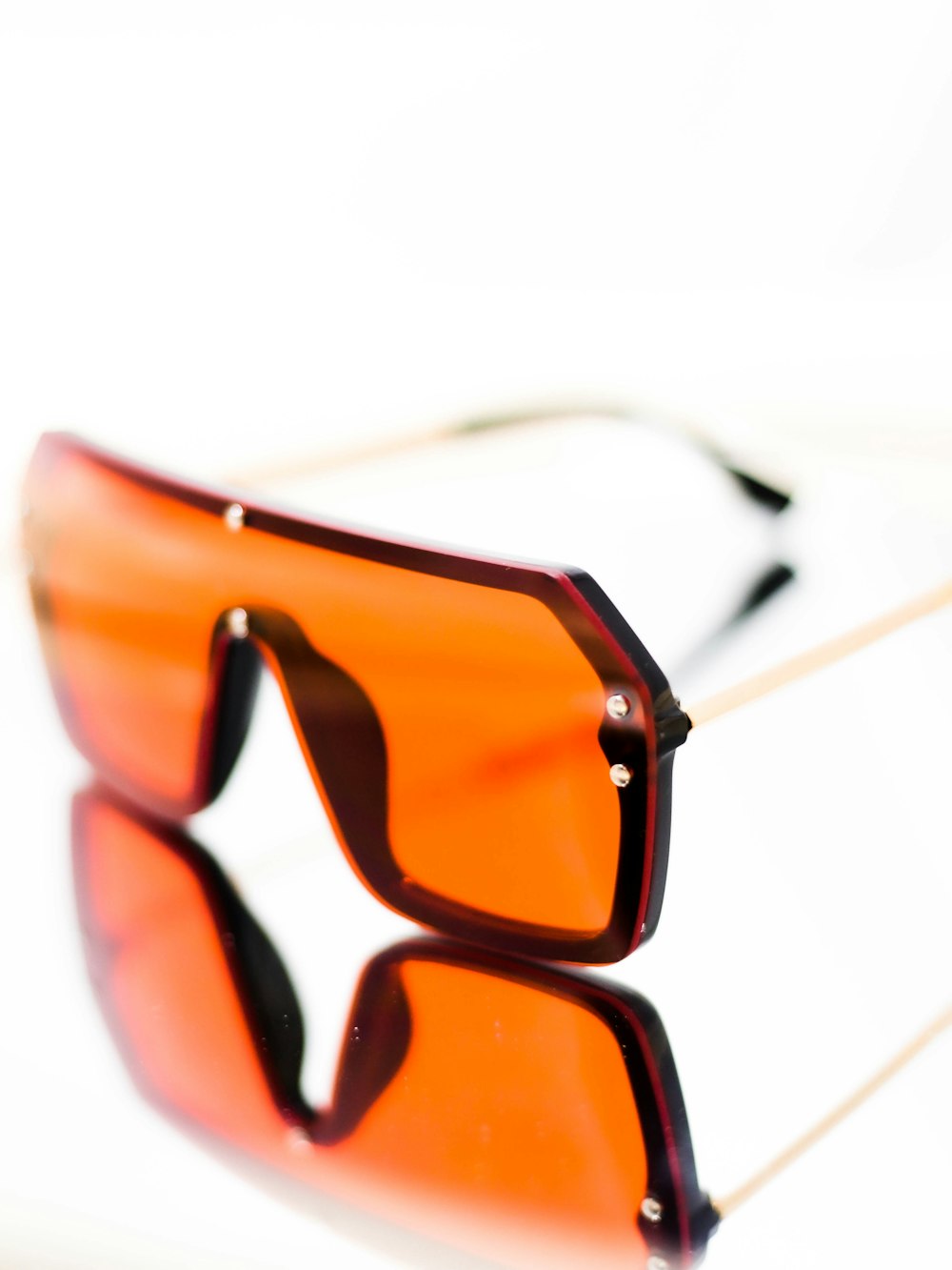 óculos de sol com armação marrom na superfície branca