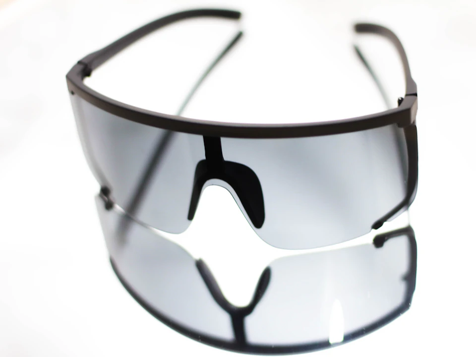 Black sunglasses resting on a white surface with sleek, modern design and curved top