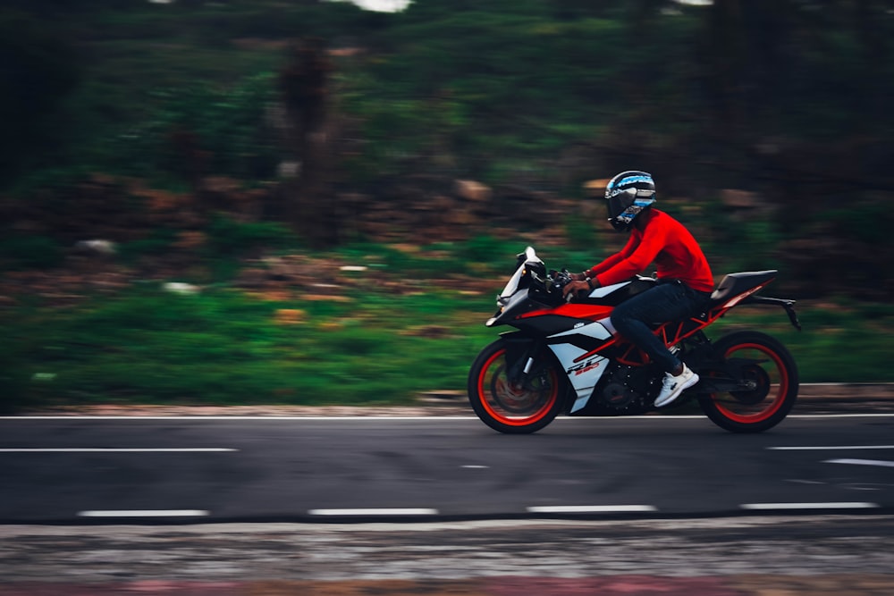 昼間の道路でバイクに乗る赤いジャケットの男