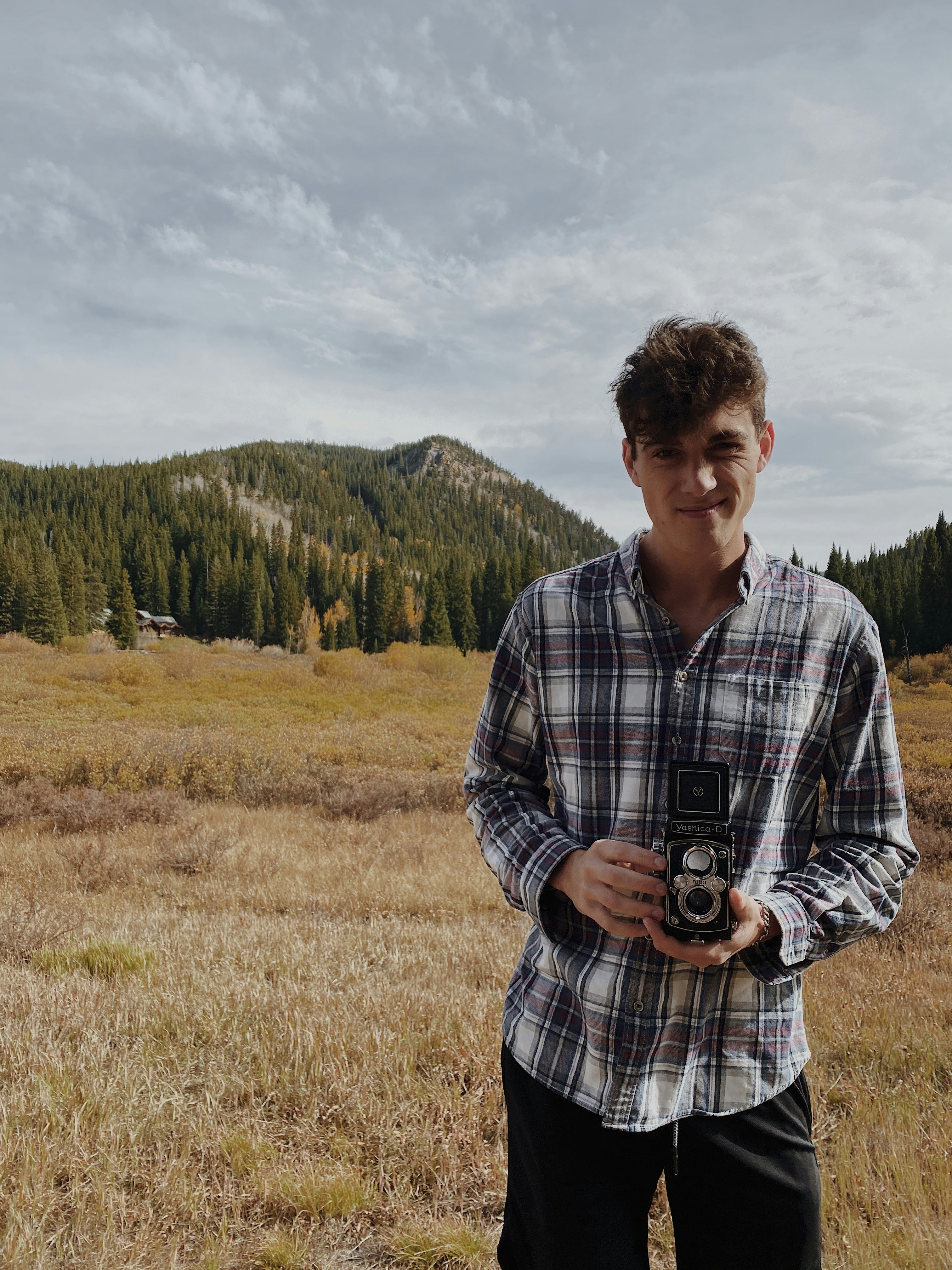 hombre en camisa de vestir a cuadros blanco y negro de pie en el campo de hierba verde durante el día