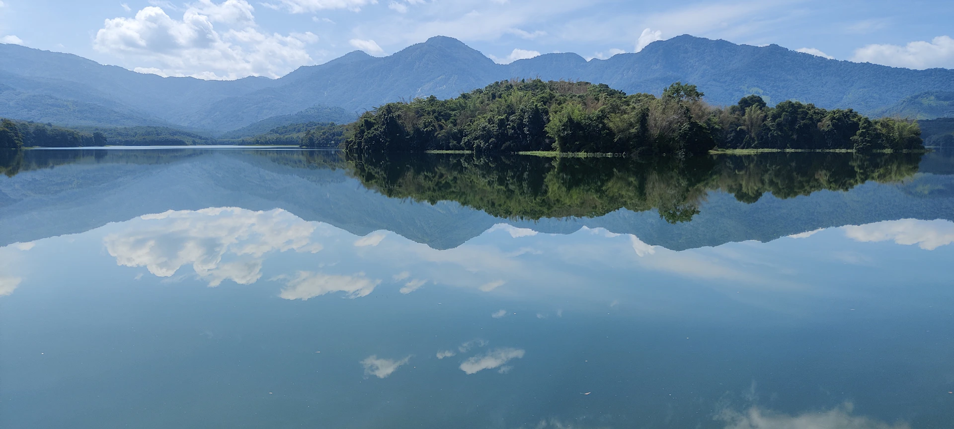 A perfectly centered photo of a serene mountain lake reflecting the clear blue sky without any distortion.