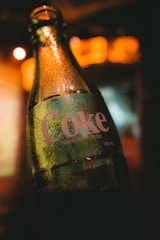 A close-up of a soda bottle wrapped in clear, protective plastic packaging.