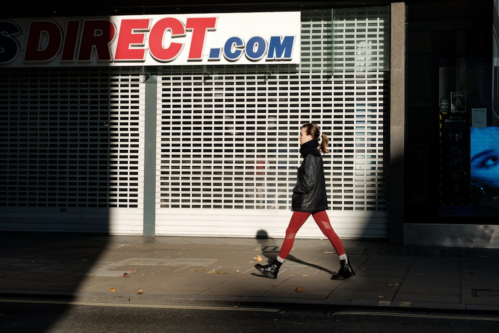 a woman walking down the street in front of a store
