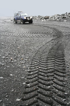 A sleek autonomous ground vehicle navigating a rugged outdoor terrain under cloudy skies.