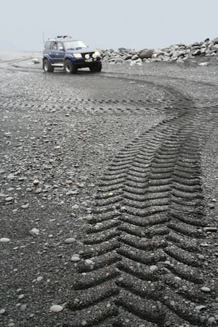 An armored tactical vehicle navigating rugged terrain under a cloudy sky.