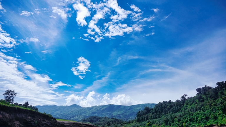 A vibrant landscape of lush green mountains under a blue sky.