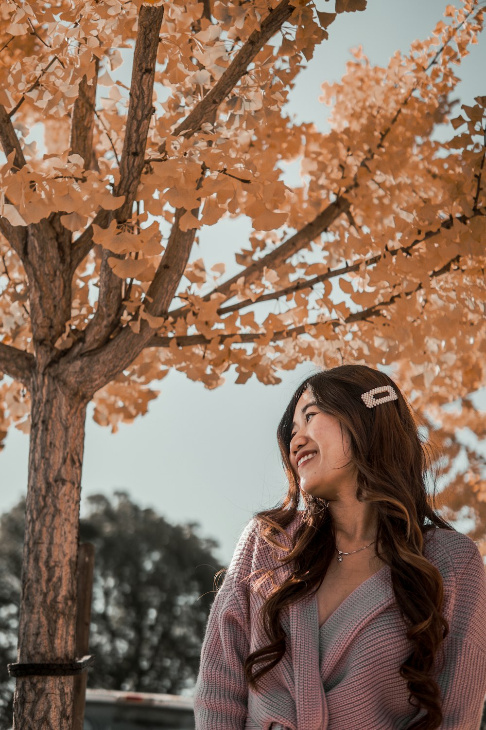 woman in black and white striped shirt standing under brown tree during daytime