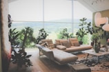 A spacious living room with large windows showcasing lush green hills.