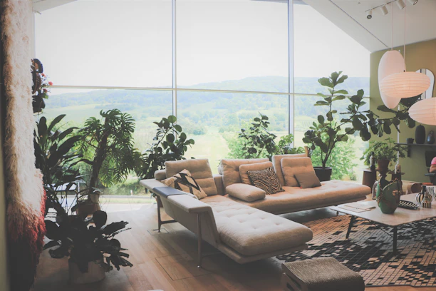 A cozy modern living room with large windows showcasing a beautiful garden view.