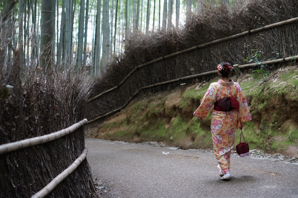 woman in blue and white floral dress walking on gray concrete road during daytime