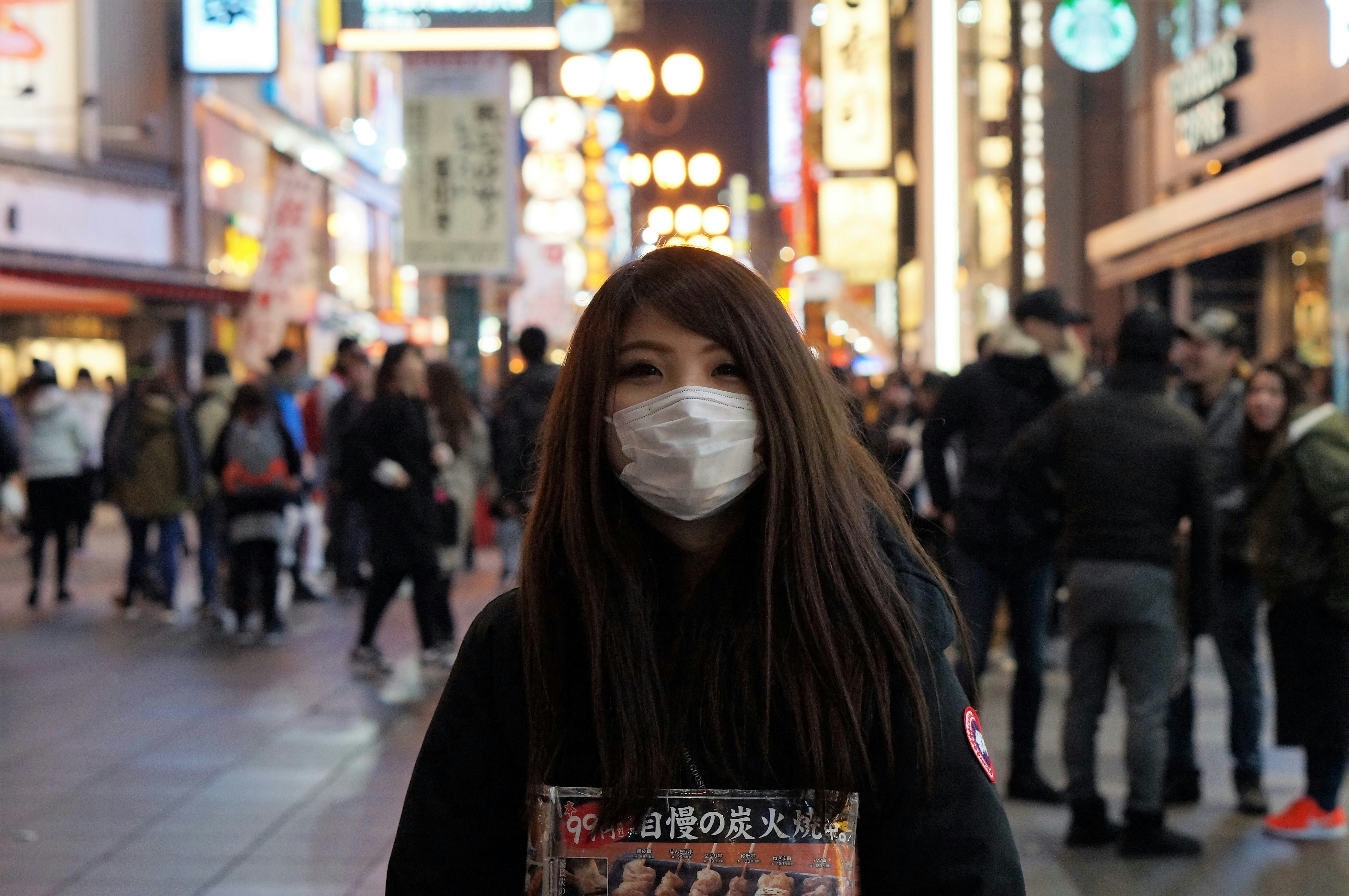 Person wearing a face mask in Japan during winter, blurred background of city street