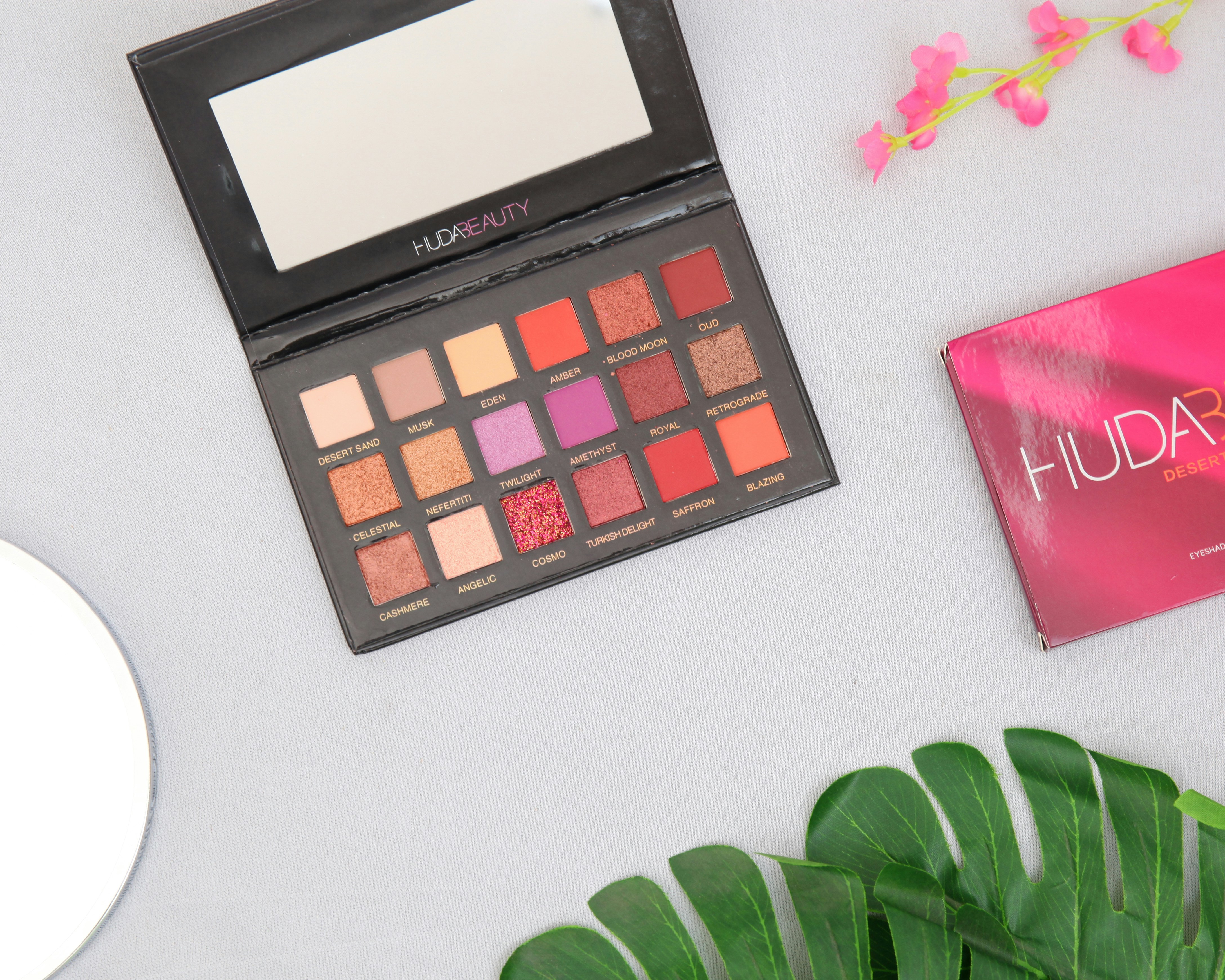 Eyeshadow palette with warm gold and rose tones open on pink surface