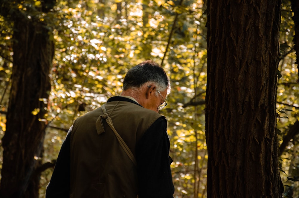 man in brown jacket standing near brown tree during daytime