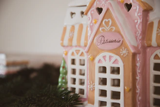 A charming pastel-colored music box shaped like a tiny house with painted windows.
