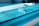 A laboratory setting featuring a conveyor belt with several test tubes placed upright in holders. The tubes are arranged in a line and have labels with barcodes. The lighting creates a cool blue tone across the surface, suggesting a sterile and clean environment.