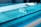 A laboratory setting featuring a conveyor belt with several test tubes placed upright in holders. The tubes are arranged in a line and have labels with barcodes. The lighting creates a cool blue tone across the surface, suggesting a sterile and clean environment.