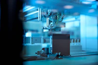 industrial robotic arm in blue lit factory