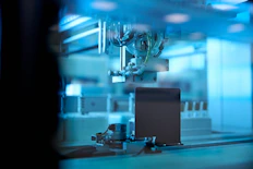 industrial robotic arm in blue lit factory