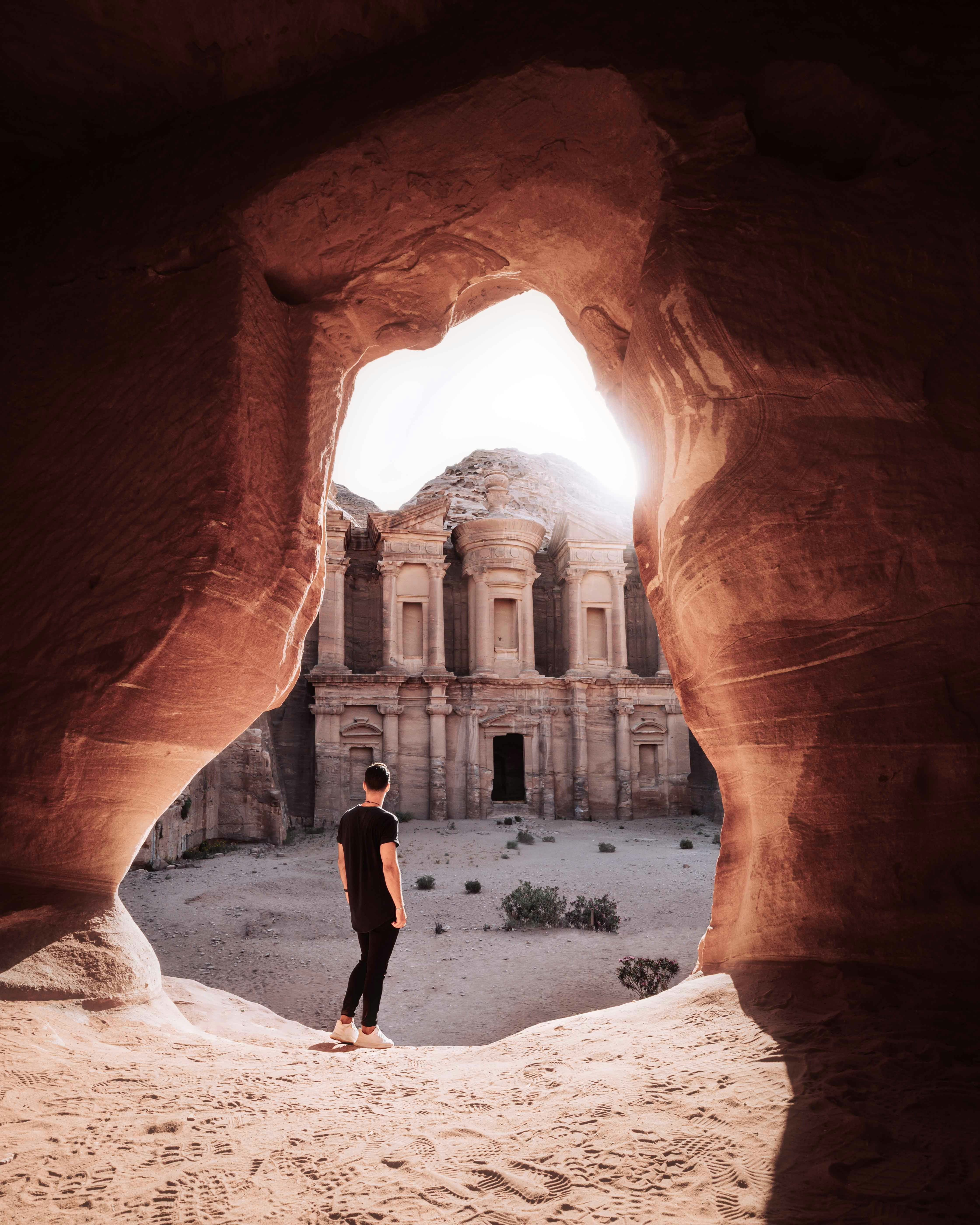 man in black shirt standing in the middle of brown rock formation during daytime