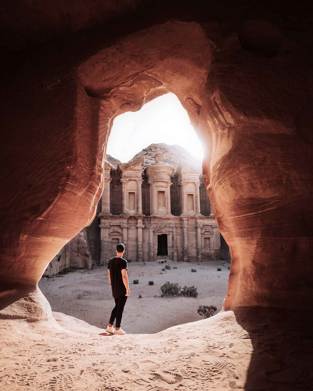 man in black shirt standing in the middle of brown rock formation during daytime