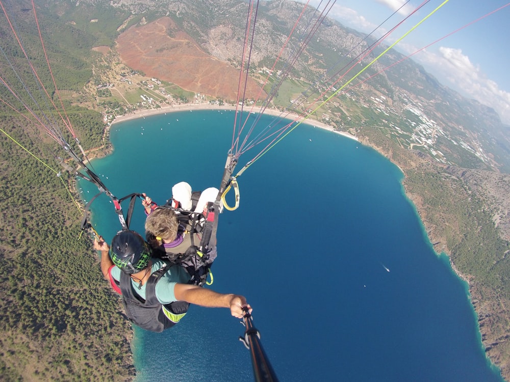 man in white shirt riding on parachute over blue sea during daytime