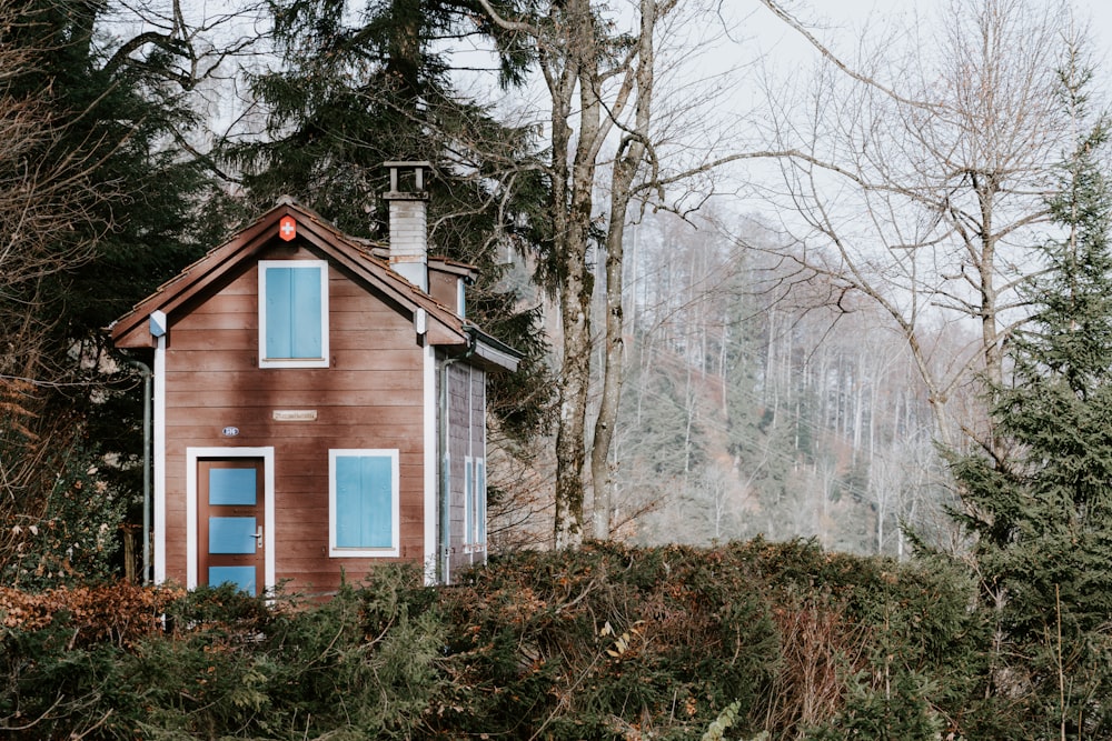 brown and white wooden house near bare trees during daytime