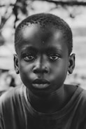 Black and white portrait of a child with expressive eyes, highlighting emotion and texture.