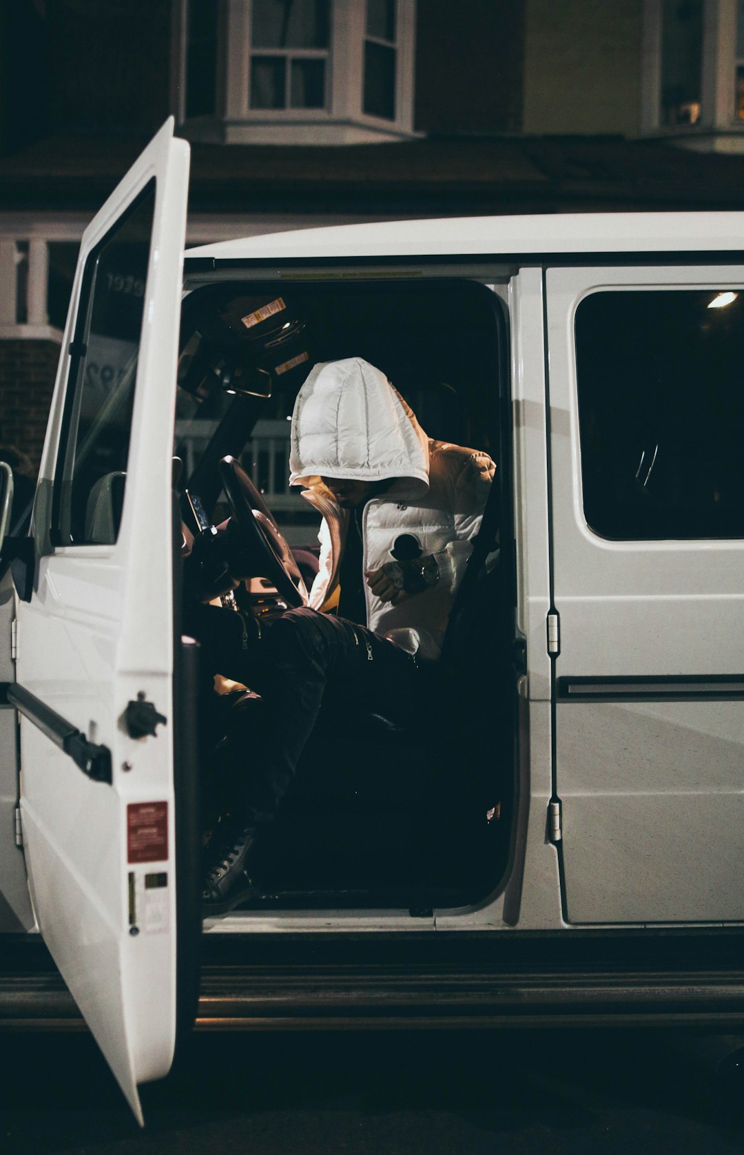 man in white dress shirt driving white van during daytime