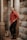 man in red dress shirt and black denim jeans sitting on concrete column