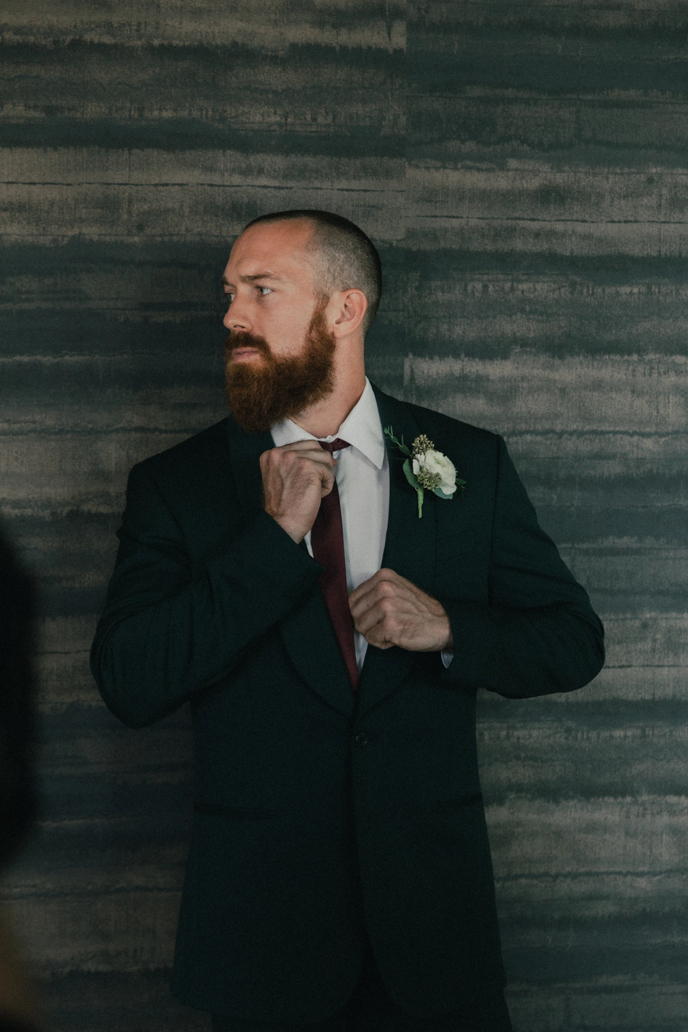 Groom in a black suit jacket standing and waiting with a calm composed expression before the wedding ceremony