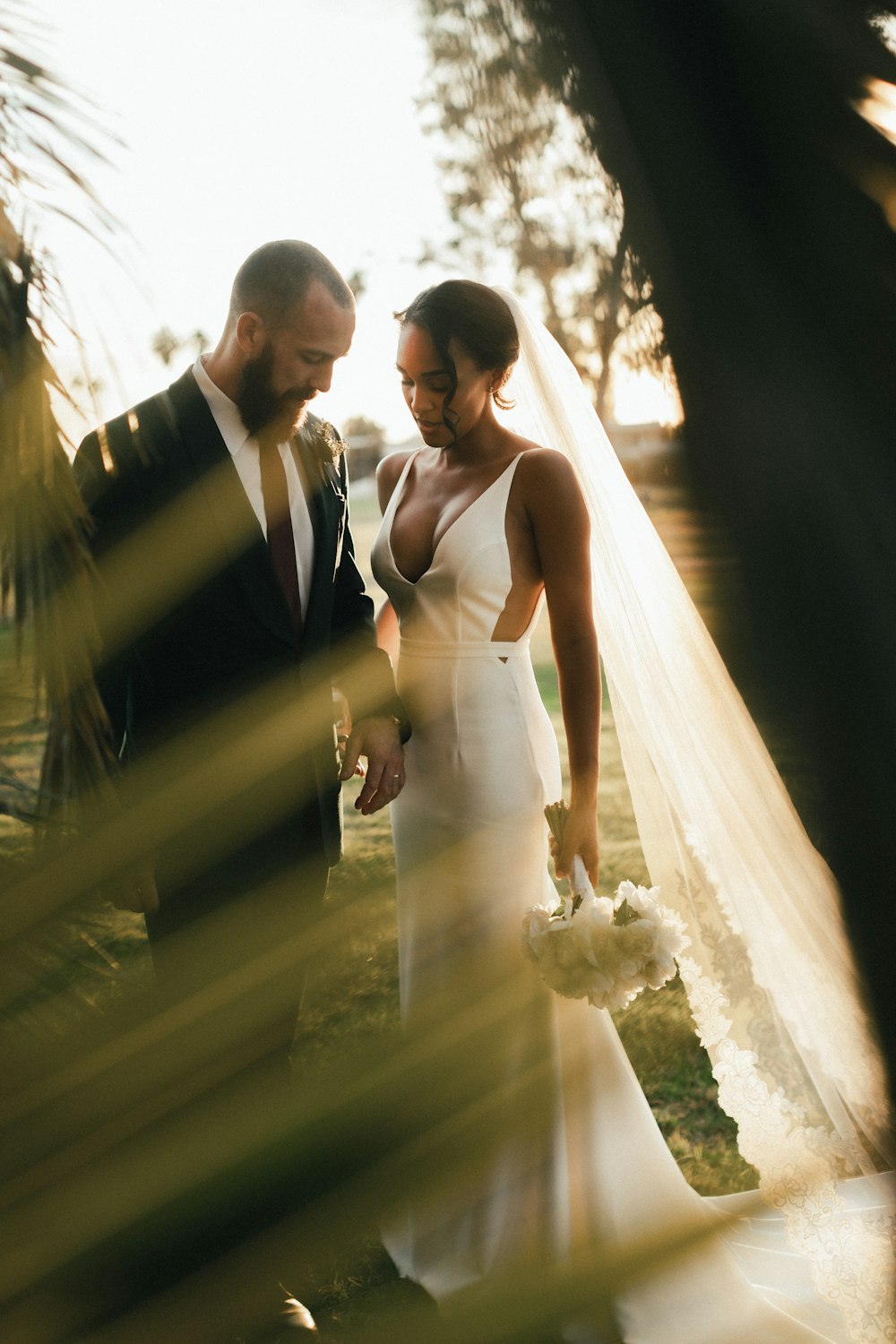 man in black suit holding woman in white wedding dress