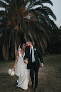 a newly married couple walking through a field