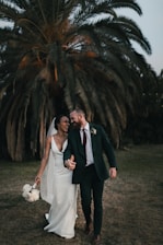 a newly married couple walking through a field