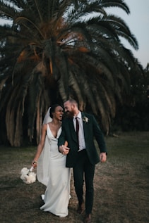 a newly married couple walking through a field