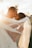 A couple is embracing intimately, with soft sunlight creating a warm, ethereal glow around them. The bride’s veil billows gracefully in the breeze, and both individuals have joyful, serene expressions as they share a close moment.