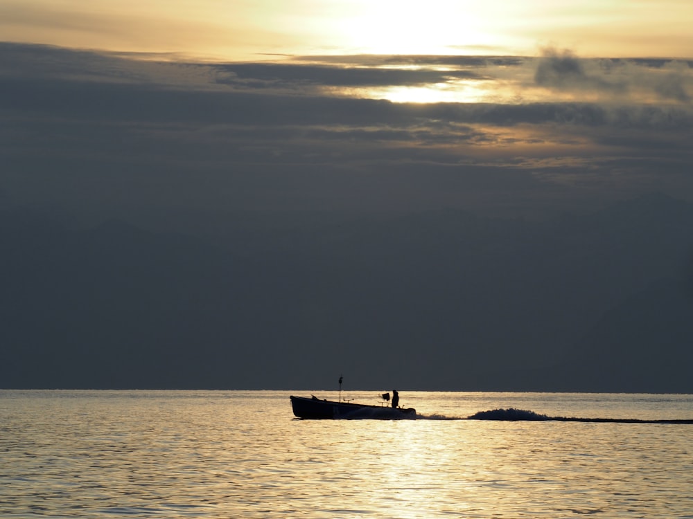 silhouette of person riding on boat on sea during sunset