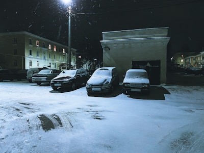 A parking lot being cleared by heavy snow removal equipment under streetlights.