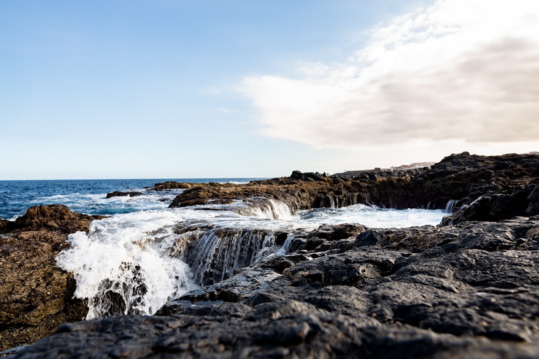 ocean waves crashing on rocks under blue sky during daytime