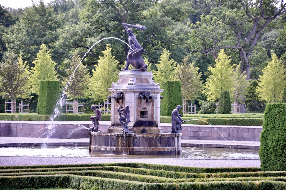 brown concrete statue near green trees during daytime