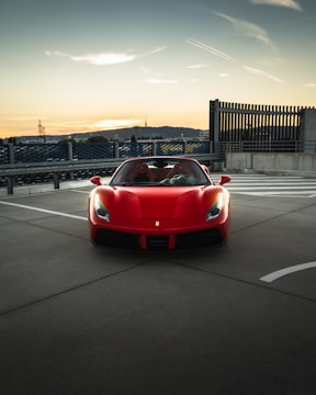 A sleek red sports car parked on a city street at sunset.