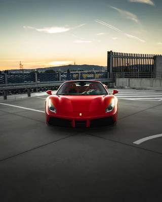 Sleek red sports car parked on a city street at sunset