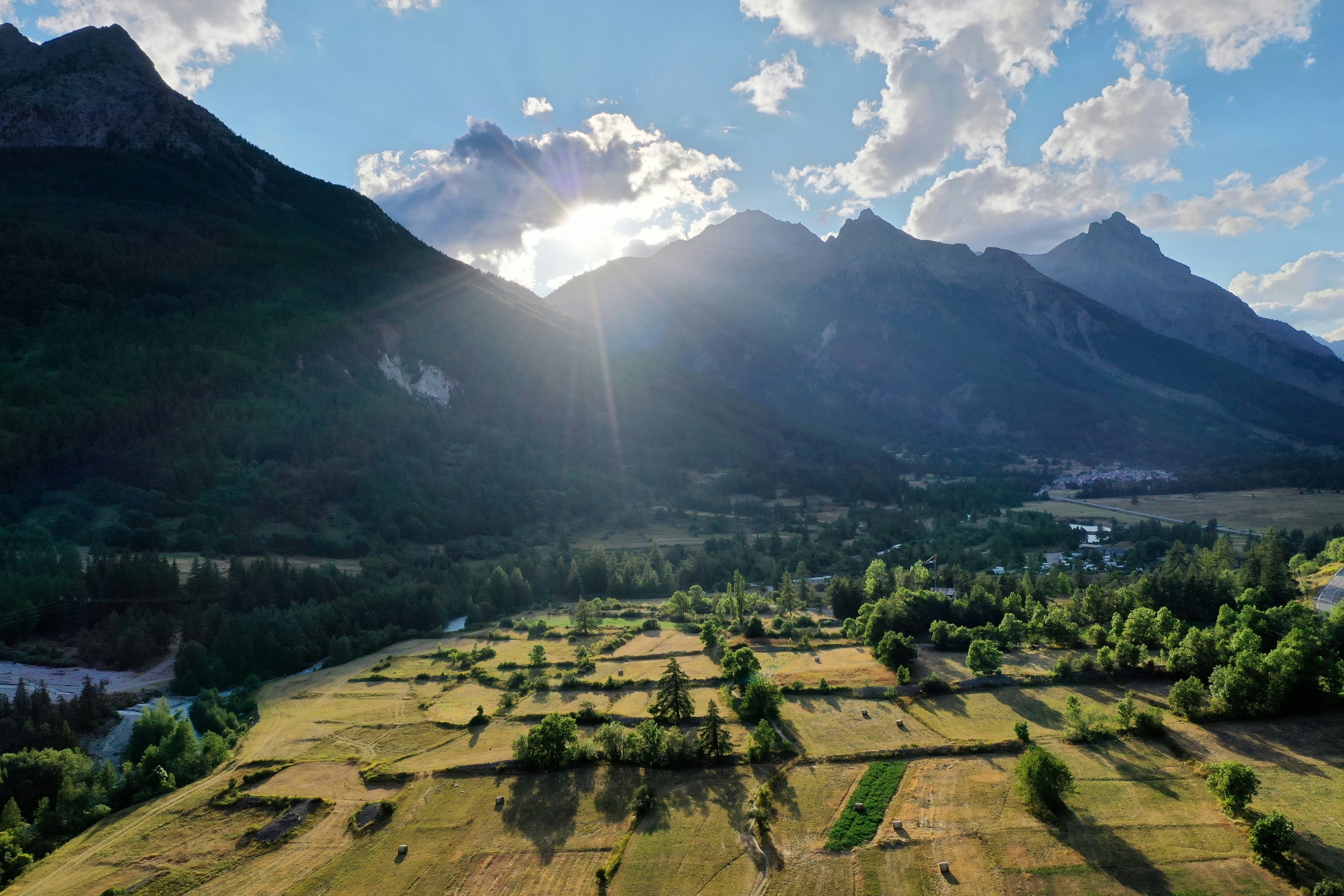 green grass field near mountain under white clouds and blue sky during daytime, 