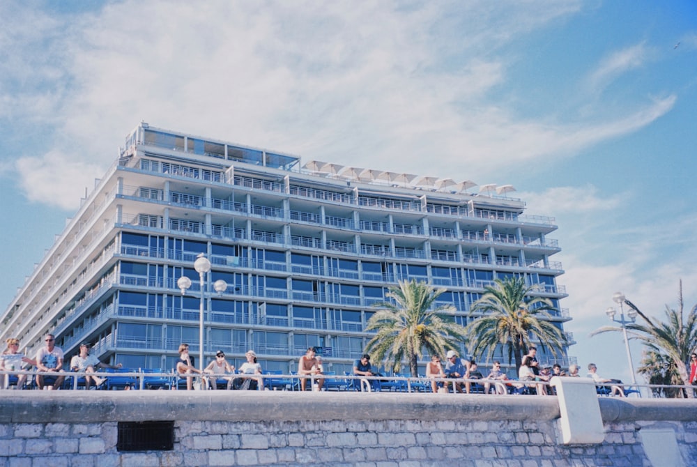 people sitting on concrete bench near white concrete building during daytime