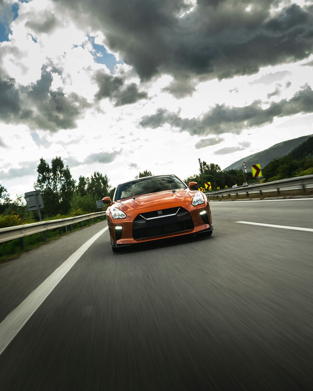 orange car on road under cloudy sky during daytime