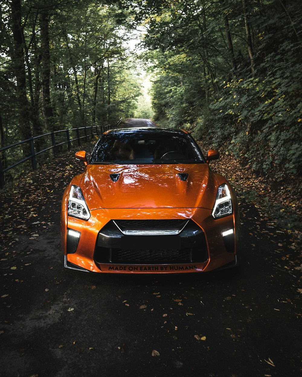 BMW M 3 naranja aparcado en el bosque durante el día